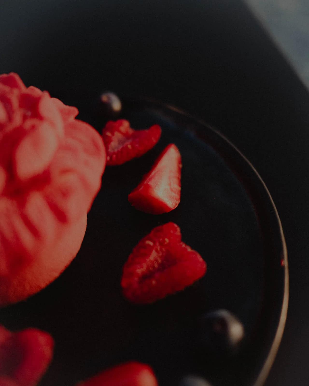 Dessert glacé en forme de rose, entouré de fruits rouges frais